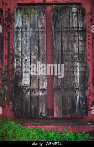 Close up view of weathered wooden planks fastened to a rusted red metal industrial structure Stock Photo