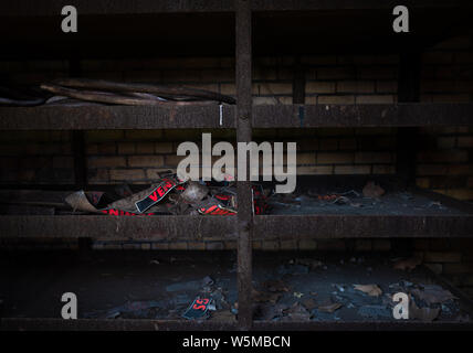 Old rusty metal shelving unit with remnants of discarded signs inside a dark abandoned industrial space Stock Photo