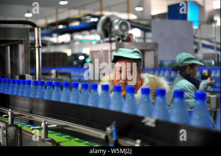 --FILE--A Chinese worker checks bottles of Wahaha purified water on the ...