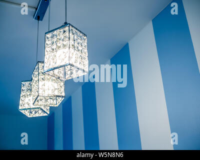 Vintage ceiling lamp on white and blue striped wall background with copy space. Stock Photo