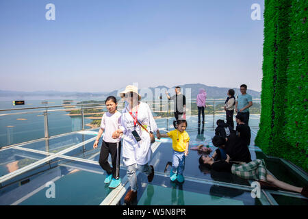 Tourists enjoy the scenery on the 99-meter-high glass tour tower at the Lushan Xihai scenic spot in Jiujiang city, east China's Jiangxi province, 7 Ap Stock Photo