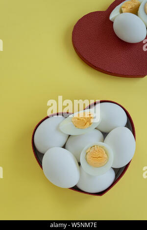 Healthy eating - eggs in heart shaped box on yellow background Stock Photo