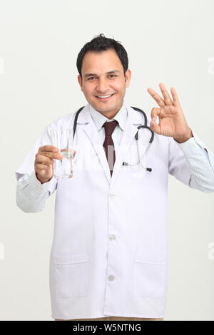 Male doctor holding a glass of water and gesturing Stock Photo