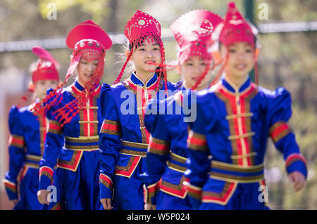 Chinese primary students dressed in traditional costumes and wearing paper-cutting headwears pose at a school in Huhhot city, north China's Stock Photo