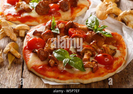 Delicious pizza with chanterelle mushrooms, mozzarella cheese, tomatoes and basil close-up on parchment on the table. horizontal Stock Photo