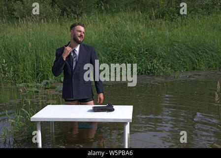 lazy young millennial man tired of boring work. Feels stressful and wants to escape home. He standing in the swamp, in the water Stock Photo
