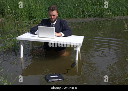 Tired bored student or employee working with a laptop, performing boring routine monotonous work. Feels desperate Stock Photo