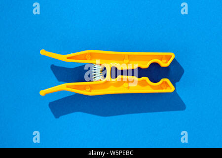 colorful orange open clothes peg on blue backgournd Stock Photo