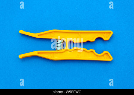 colorful orange open clothes peg on blue backgournd Stock Photo