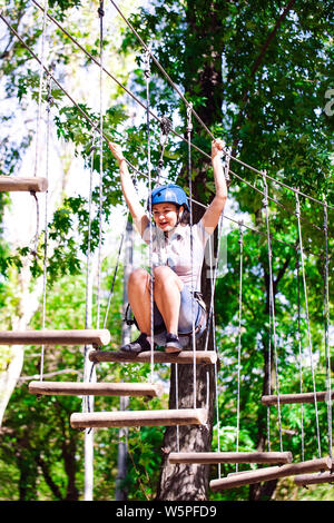 adventure climbing high wire park - people on course in mountain helmet and safety equipment Stock Photo