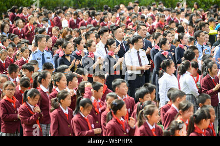 Primary school students, flight attendants and pilots from China Eastern Airlines gather to encircle a national flag on the Chinese Valentine's Day in Stock Photo