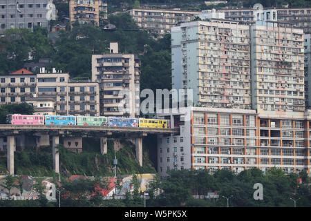 --FILE--A monorail train drives out from a building at the Liziba Station of Chongqing Light Rail Line 2 in Chongqing, China, 13 May 2018. Stock Photo