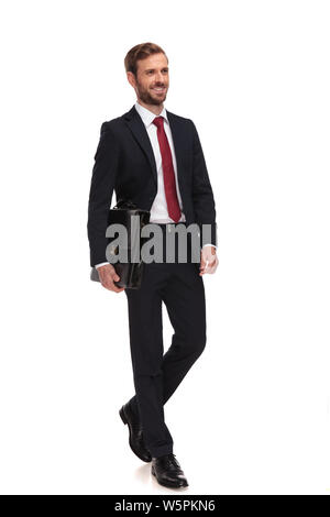 young businessman holding briefcase steps on white background and looks to side, full length picture Stock Photo