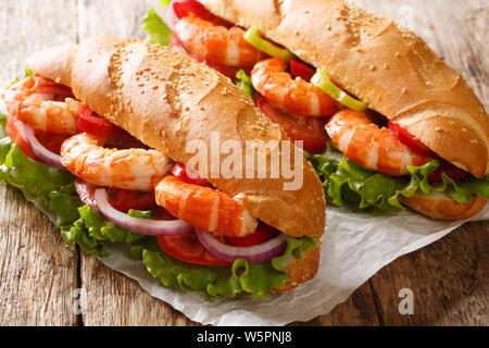 Healthy sandwiches with king prawns, summer vegetables close-up on paper on the table. horizontal Stock Photo