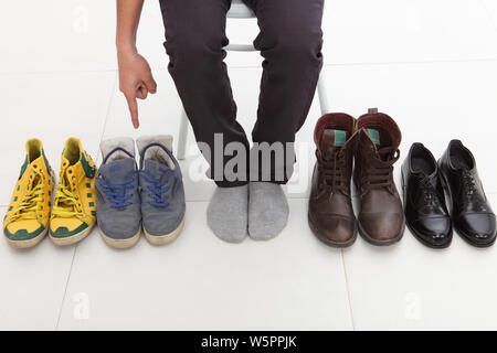 Low section view of a man deciding which shoes to wear Stock Photo