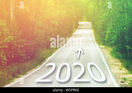 Concept for new year 2020. Word 2020 written on highway road in the middle of empty asphalt road at golden sunset. Stock Photo