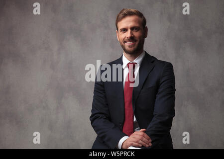 young businessman smiling and posing against grey studio wallpaper Stock Photo