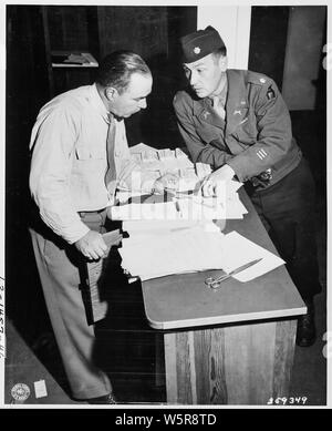 Lt. Col. James P. Smith, Jr. of Ipswich, Massachusetts, Provost Marshall of the Berlin District, left, and Major William J. E. Keish, Commanding Officer, 713th MP Bn., whose home is Brooklyn, New York, check pass lists for the Potsdam Conference area in Potsdam, Germany. Stock Photo