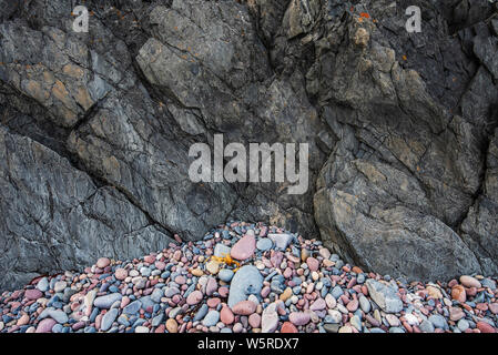 Natural seashore stones and dark slate rock. Arctic Ocean coastline in Varanger peninsula, Finnmark, Norway Stock Photo