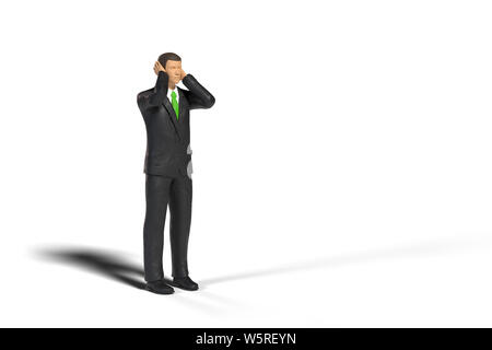 toy miniature businessman figure covering his ears in front of empty space, concept isolated with shadow on white background Stock Photo