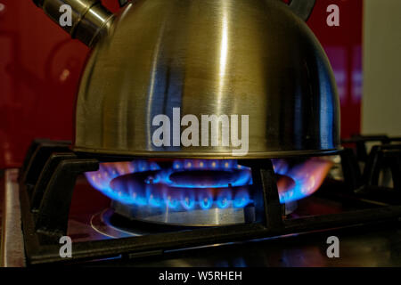 A kettle boiling water on a gas hob. Now we're cooking with gas. Stock Photo