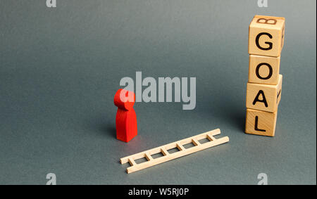 tower of cubes with an inscription goal and a red figure of a man stands near fallen ladder. concept of achieving the goal, subject to the application Stock Photo