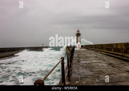 Waves of the sea breaking against the lighthouse of Oporto, on rainy and windy days. Stock Photo