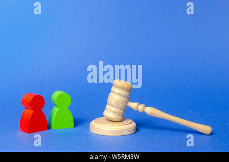 Two figures of people opponents stand near the judge's gavel. The judicial system. Court case, settling disputes. Legal advice, lawyer services. Confl Stock Photo