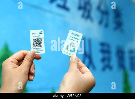 Local residents shows QR code cards used to open different bins to put their garbage at a waste collection point in Shanghai, China, 19 June 2019.   S Stock Photo