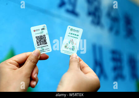 Local residents shows QR code cards used to open different bins to put their garbage at a waste collection point in Shanghai, China, 19 June 2019.   S Stock Photo