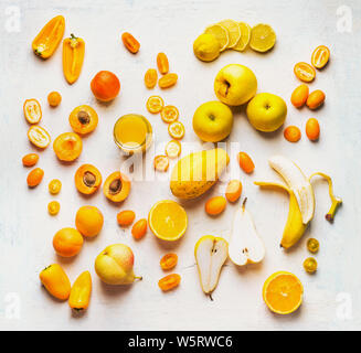 Various yellow and orange color fruits and vegetables on white table background. Flat lay. Food layout. Color diet. Benefits of yellow and orange colo Stock Photo