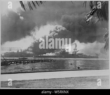 Naval photograph documenting the Japanese attack on Pearl Harbor, Hawaii which initiated US participation in World War II. Navy's caption: The smoldering battleship USS NEVEDA silhouetted in the fire and smoke of the destroyer USS SHAW which exploded when her magazine was hit by bombs from Japanese aircraft during the attack on Pearl Harbor on Dec. 7, 1941.; Scope and content:  This photograph was originally taken by a Naval photographer immediately after the Japanese attack on Pearl Harbor, but came to be filed in a writ of application for habeas corpus case (number 298) tried in the US Distr Stock Photo