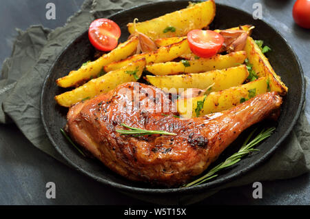Fried chicken leg and potato wedges in frying pan, close up Stock Photo