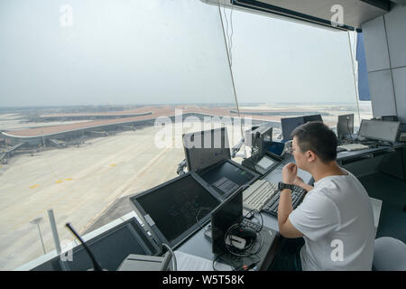 A Chinese worker is seen at the air traffic control tower, known as the 'Eye of Phoenix', at the Beijing Capital International Airport in Beijing, Chi Stock Photo
