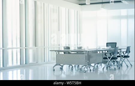 Modern Interior meeting room with evening sunset light from clean glass windows, empty large conference space with chairs and tables furniture, busine Stock Photo