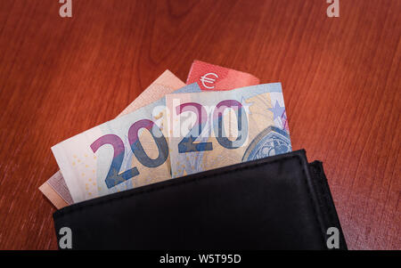 Close up of black wallet on wooden table with euro banknotes Stock Photo