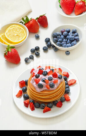 Pancakes with fruit yogurt, fresh strawberry and blueberry on white plate Stock Photo