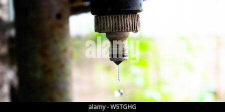 A water drop falls from a dirty and rusty water tap - Water engineering theme Stock Photo