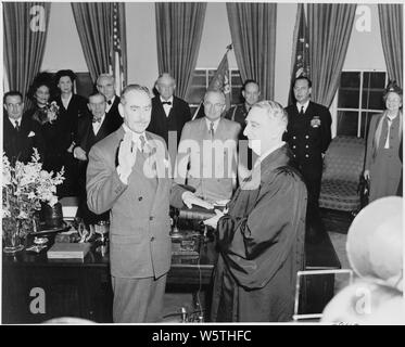 Photograph of Dean Acheson taking the oath of office as Secretary of State, with Chief Justice Fred Vinson administering the oath while President Truman and others look on in the Oval Office. Stock Photo