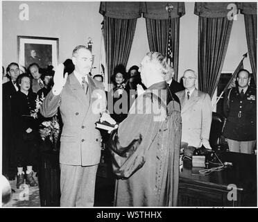 Photograph of Dean Acheson taking the oath of office as Secretary of State in the Oval Office, with Chief Justice Fred Vinson administering the oath while President Truman and other dignitaries look on. Stock Photo