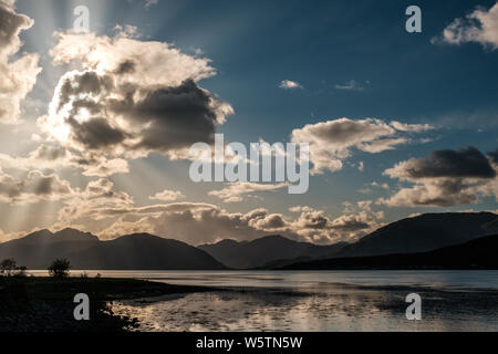 Late afternoon sun rays filtering through the clouds over Loch Linnhe in Scotland with mountains silhouetted in the distance Stock Photo