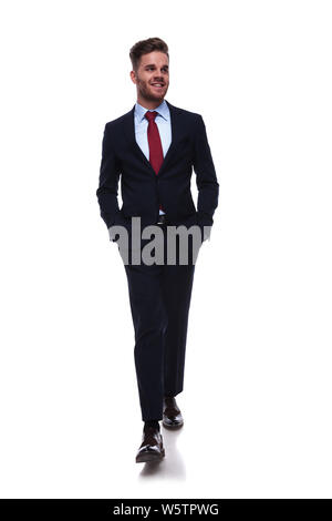 relaxed businessman in navy suit walks and looks to side, on white background Stock Photo