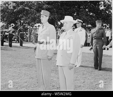 Photograph of President Truman and French President Charles de Gaulle, standing at attention during welcoming ceremonies on the White House lawn. Stock Photo