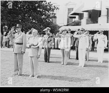 Photograph of President Truman and French President Charles de Gaulle during welcoming ceremonies on the White House lawn, with officers saluting in the background. Stock Photo