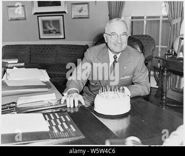 Photograph of President Truman at his desk in the Oval Office with his birthday cake, on his 67th birthday. Stock Photo