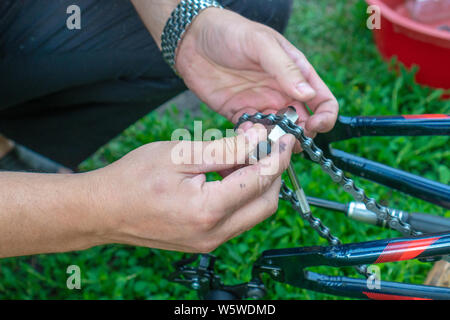 Bike repair. Young man repairing bike in the forest Stock Photo