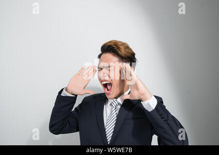 asian young business man in classic black suit shouting out loud Stock Photo