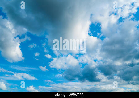 Blue dramatic sky background - white dramatic colorful clouds lit by sunlight. Vast sky landscape panoramic view Stock Photo