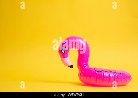 Bright pink inflatable flamingo swimming pool toy against a yellow background Stock Photo