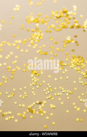 Festive golden stars of confetti are scattered on a light background. Holiday concept. Stock Photo
